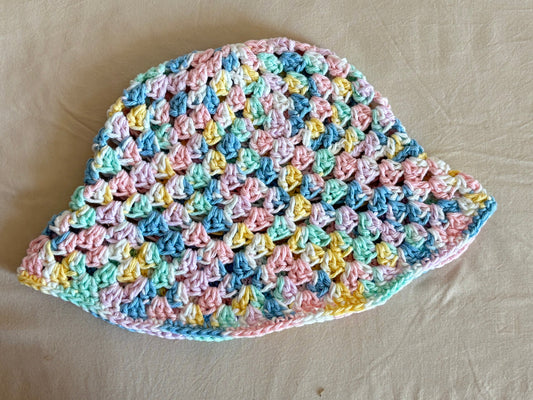 Pastel-colored crocheted dishcloth on a beige background